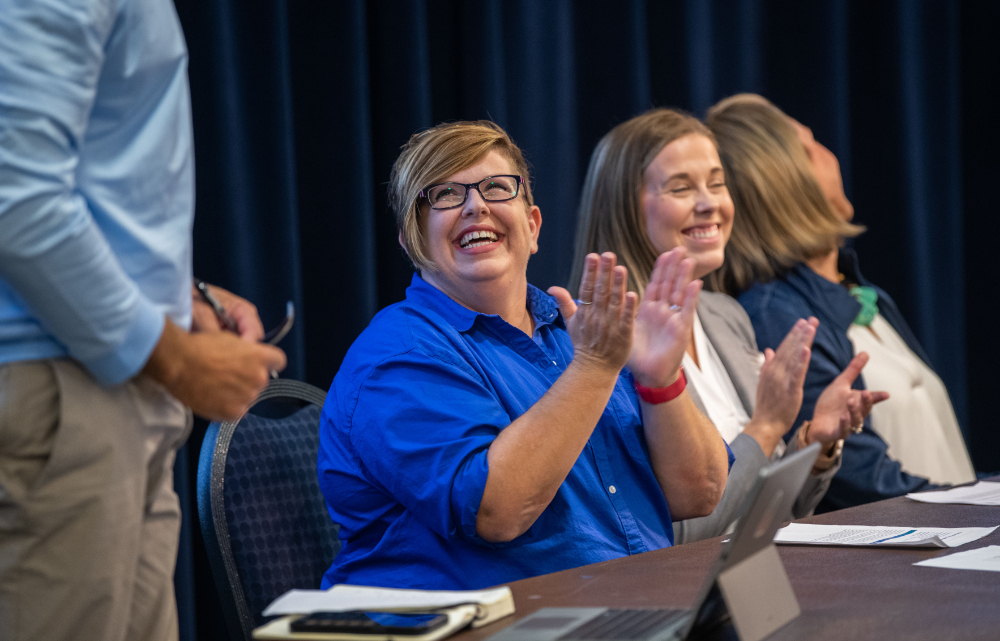 women clapping while seated at table