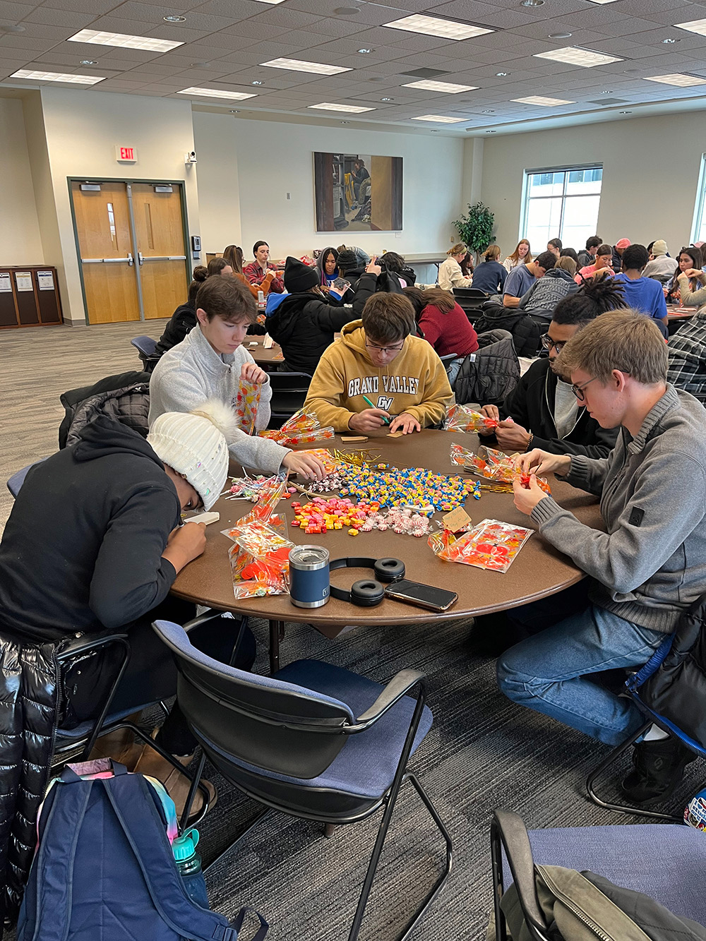 groups of students seated at tables filling bags with candy and other treats