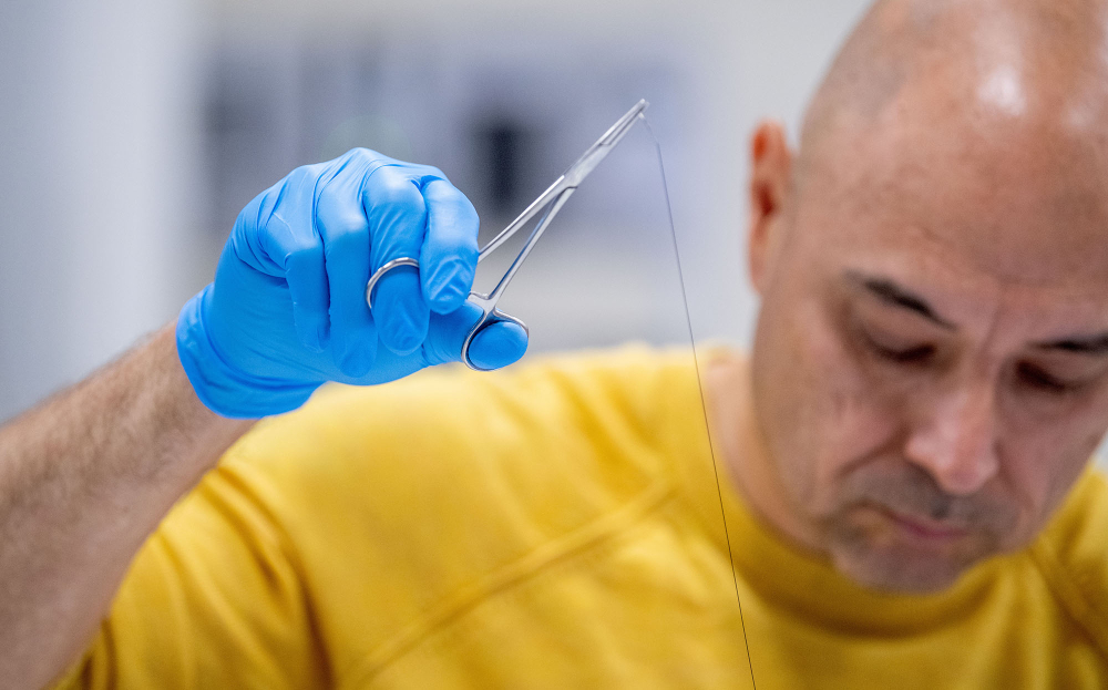 Henry Pe&ntilde;a pulls a suture during a lab, he is in a yellow shirt