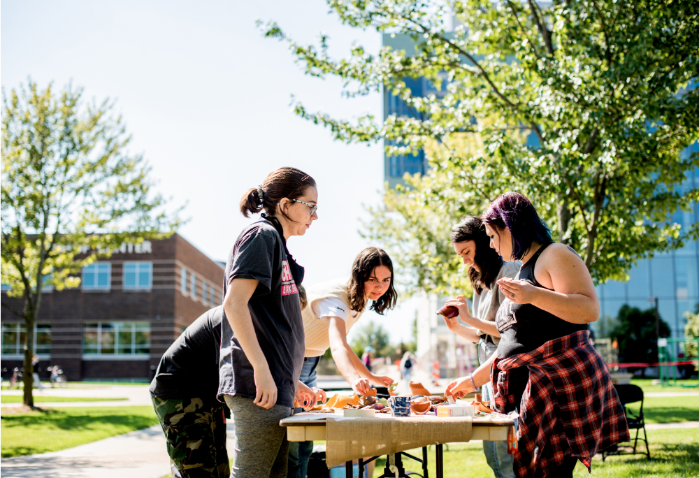 students stand around a table outside and play a game