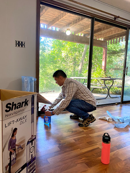 student kneels to clean a floor to ceiling slider in a house
