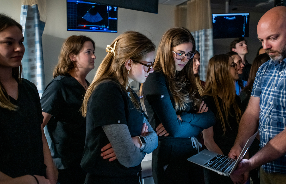 Patrick Smith, at right, holds a laptop for students to see