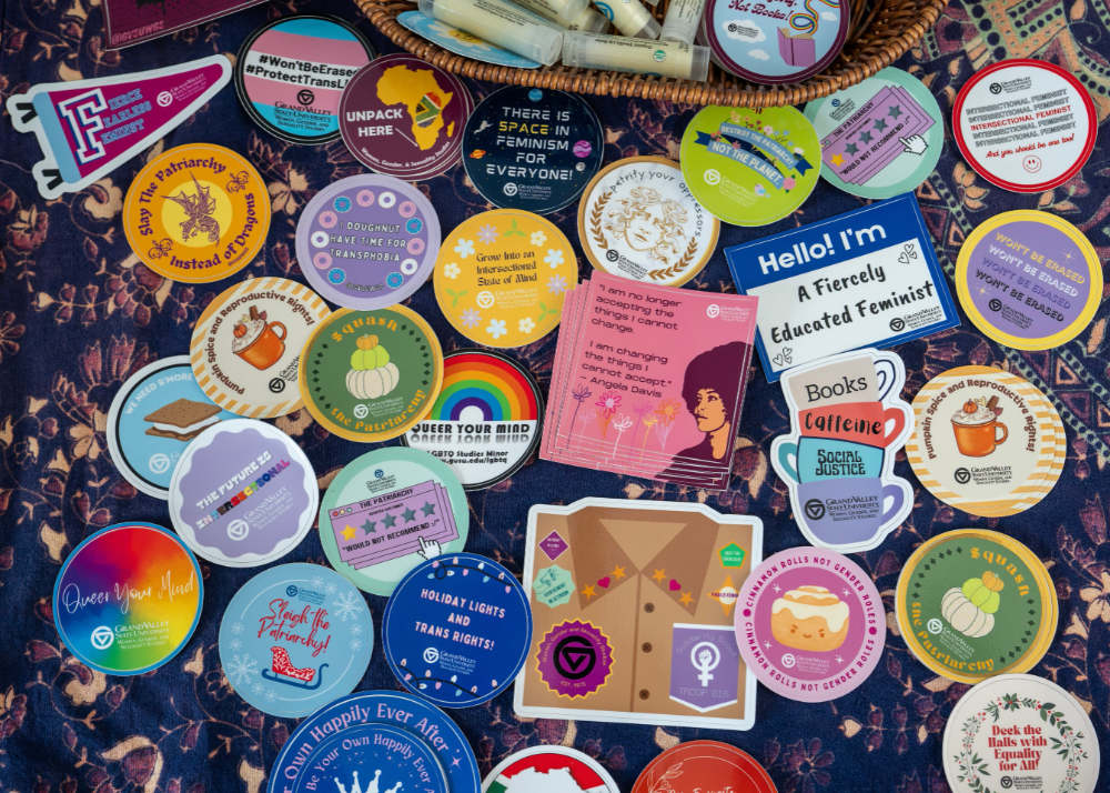 array of stickers promoting feminism and Brooks College are spread on a table