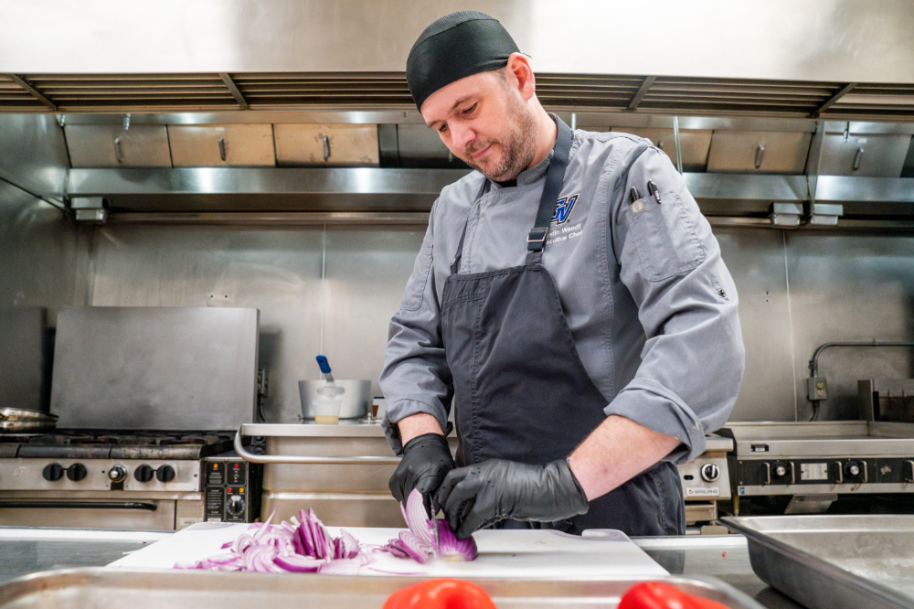 chef chopping onions in commercial kitchen