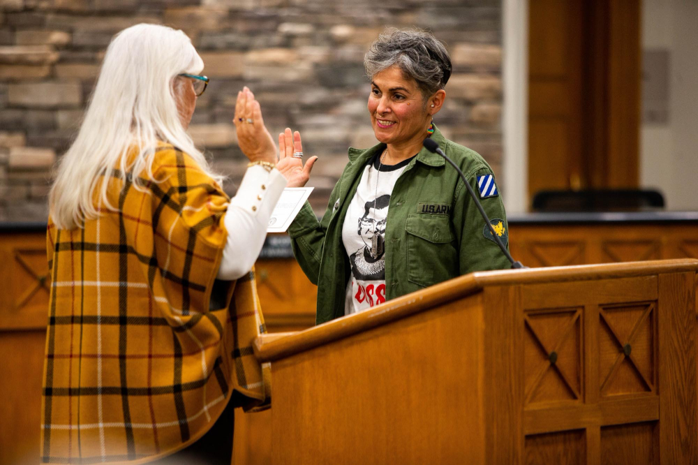 person with back to camera swearing in another person; both are standing in front of a podium