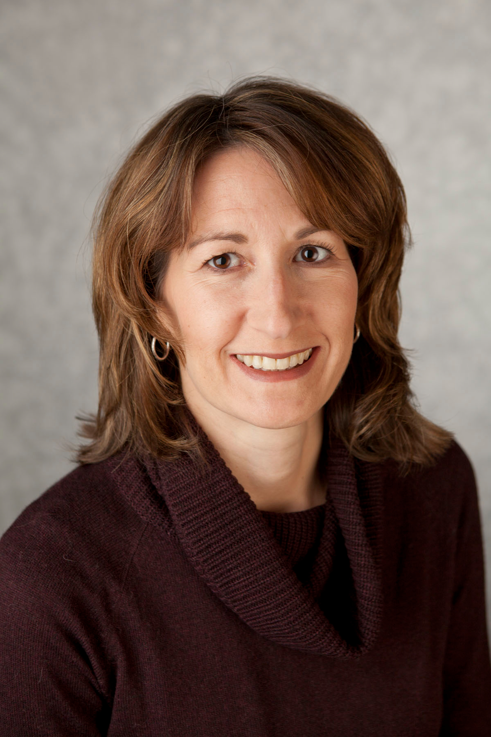 Amy Matthews seated for a portrait against a gray background