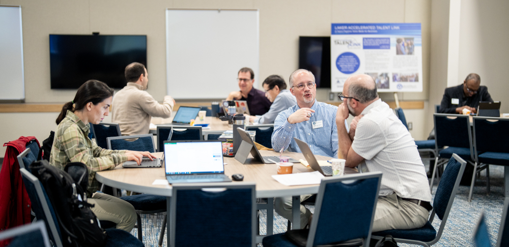 group at a table with laptops chatting and working