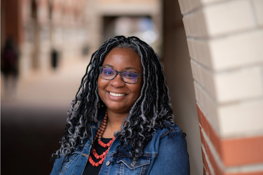 Laila McCloud, assistant professor of educational leadership and counseling, standing outside the DeVos Center wearing a denim shirt and red necklace