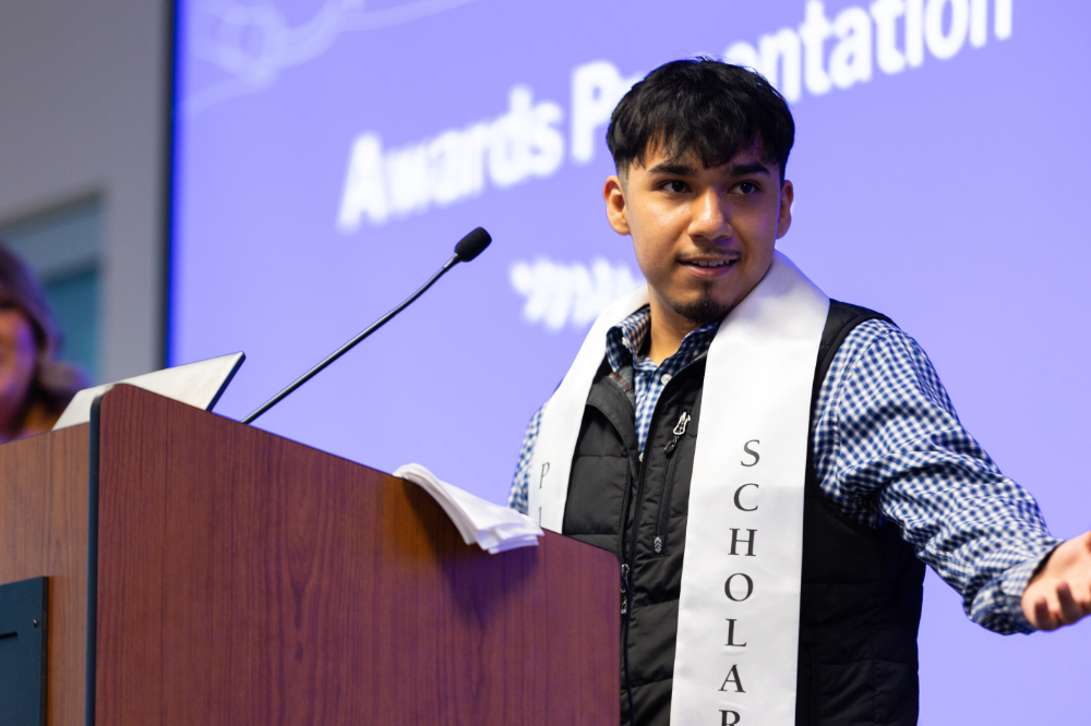 student at podium with scholar stole over his shirt and vest