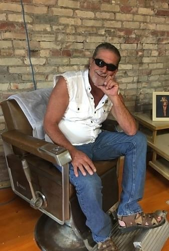 Jerry Bosch seated in chair against brick wall