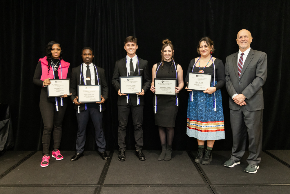 five students holding certificates, Jeff Potteiger is at far right in gray suit