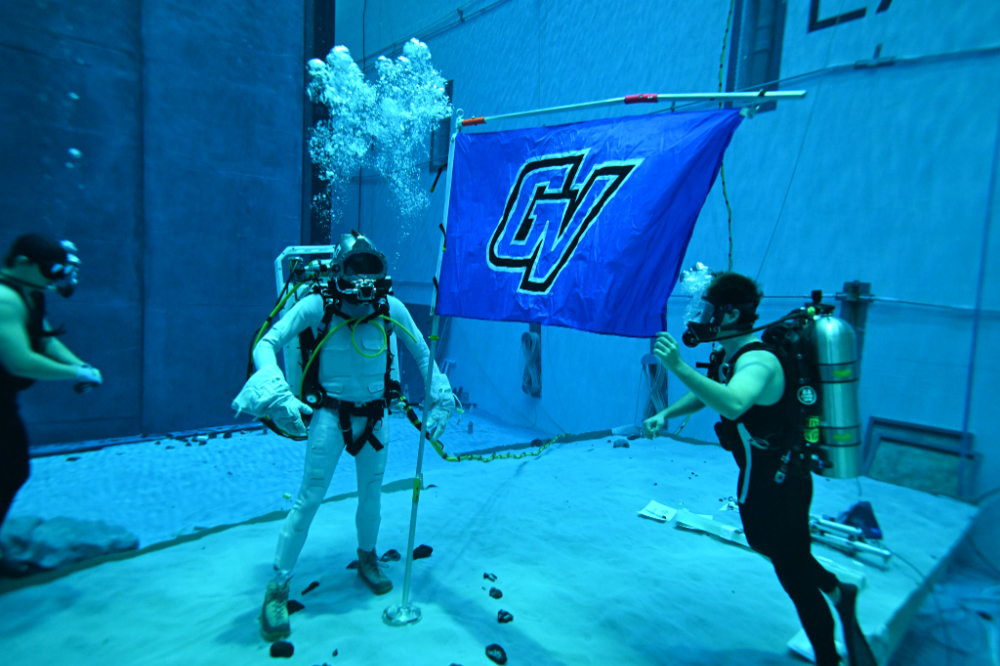 underwater photo in pool, scuba divers hoist a GV flag on a flagpole