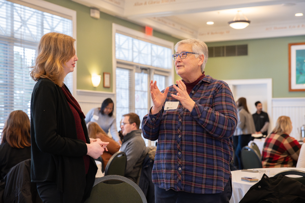 two people standing to talk, woman on right has hands up