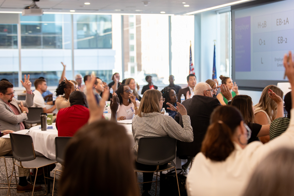 people seated at tables, some with hands raised