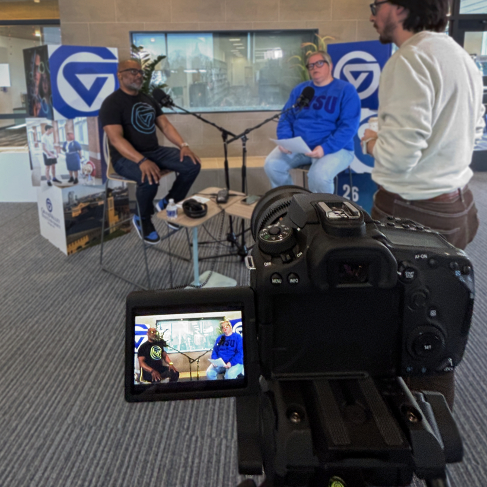 recording a podcast with Vice President B. Donta Truss and Michelle Rhodes, associate vice president of Financial Aid, seated in chairs and a camera in foreground recording them.