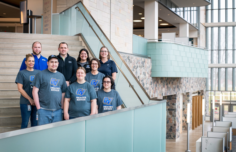 nine people standing on stairs, staggered, at Mary Idema Pew Library