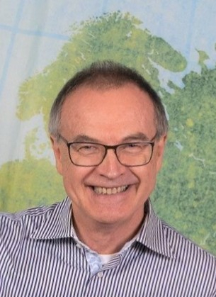 headshot of Hermann Kurthen in front of a wall map