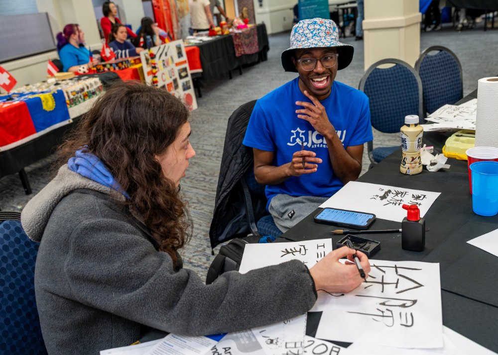 Film and video major Kobe Wright, right, helps undeclared major Emily Grob write in Japanese as part of the Global Language and Culture Festival at the Kirkhof Center on March 20.