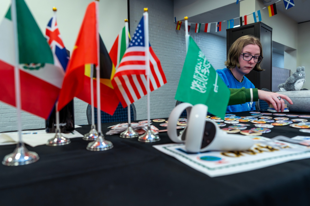 Psychology major Abigail Van Norwick works at the Language Resource Center booth during the Global Language and Culture Festival; small global flags are on the table to the left