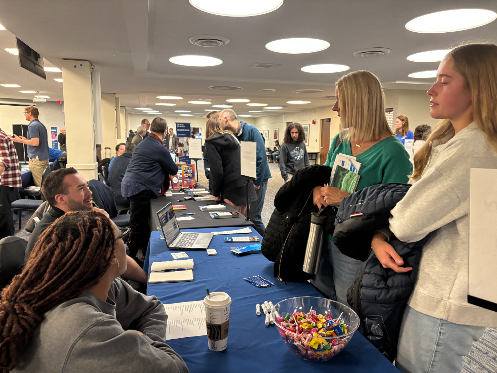 tabling event with people standing on right conversing with two people seated