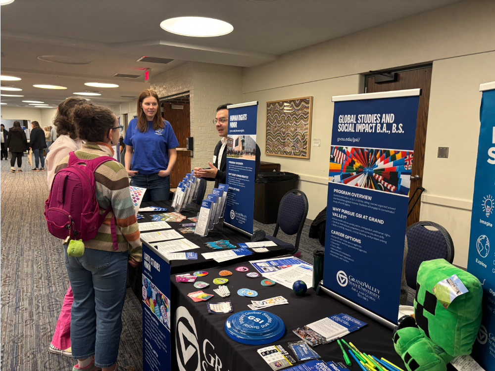 two people standing in front of the human rights minor table, with two people standing behind