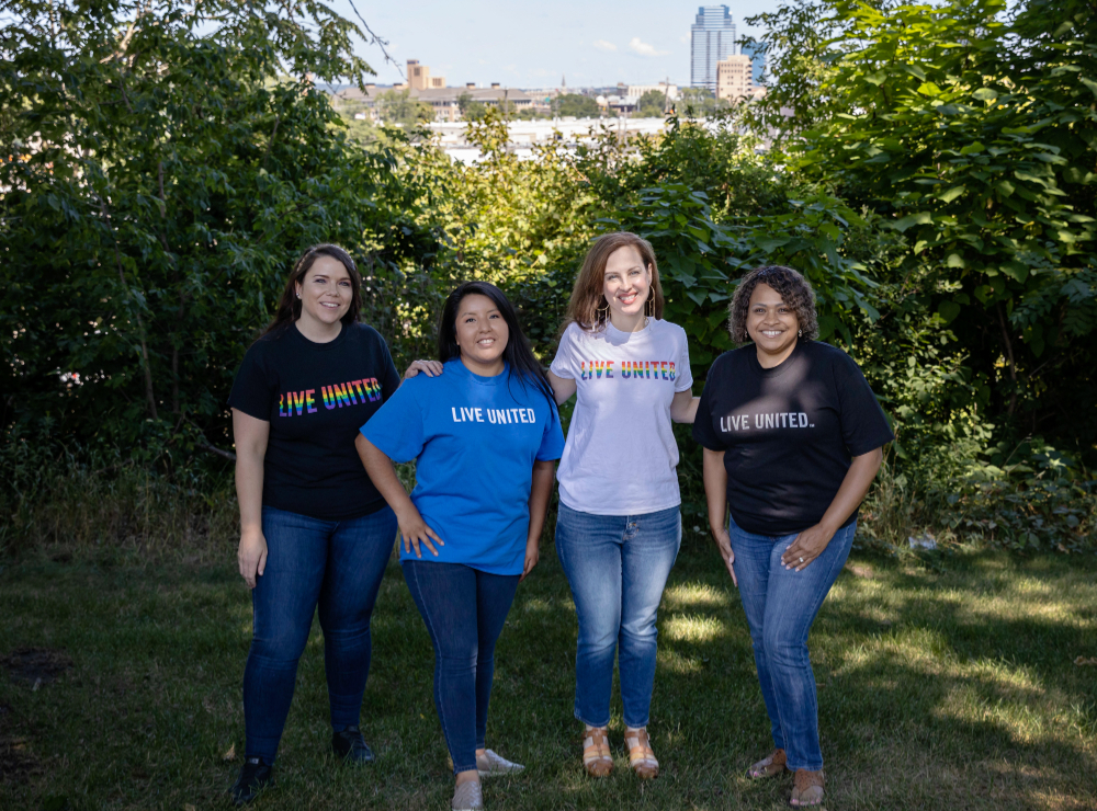four people standing outside in Live United tshirts