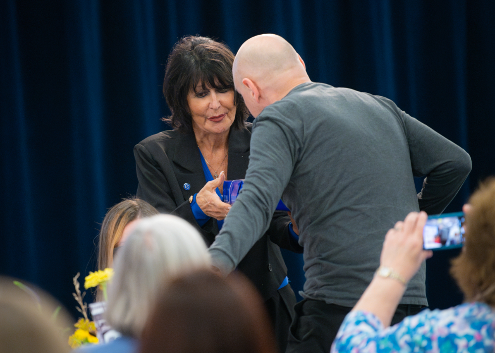 President Mantella presents a gift to man who stands from a table of people to accept it