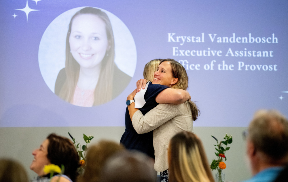 two women hugging while screen is projected in background