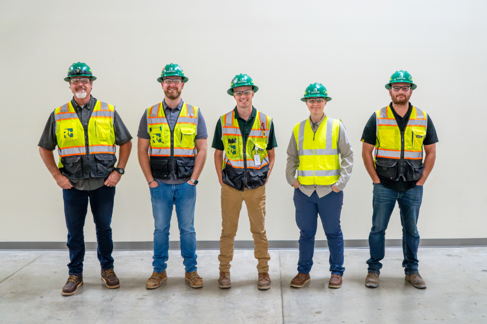 five people in safety vests and hard hats standing in line