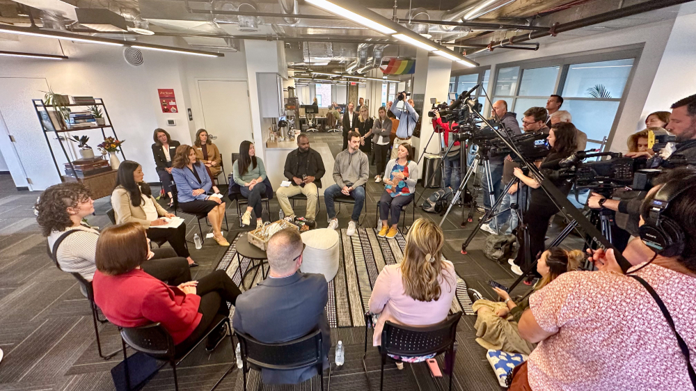 TV cameras and reporters capture a panel discussion with Gov. Whitmer