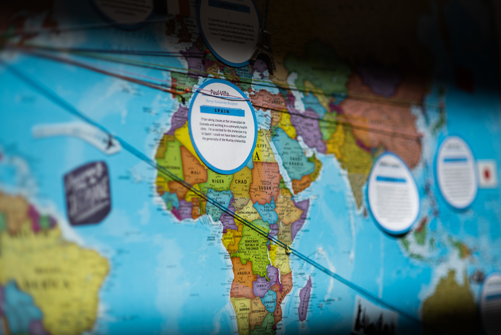 map of the world as wall poster with strings connecting names of students to various locations