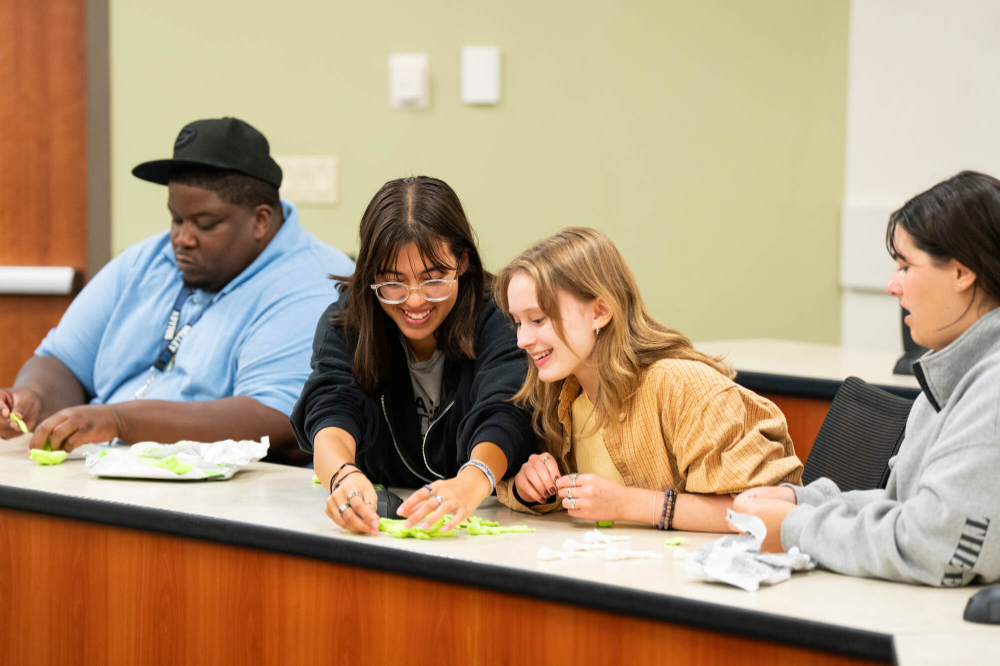 four students work on an activity with paper at a table
