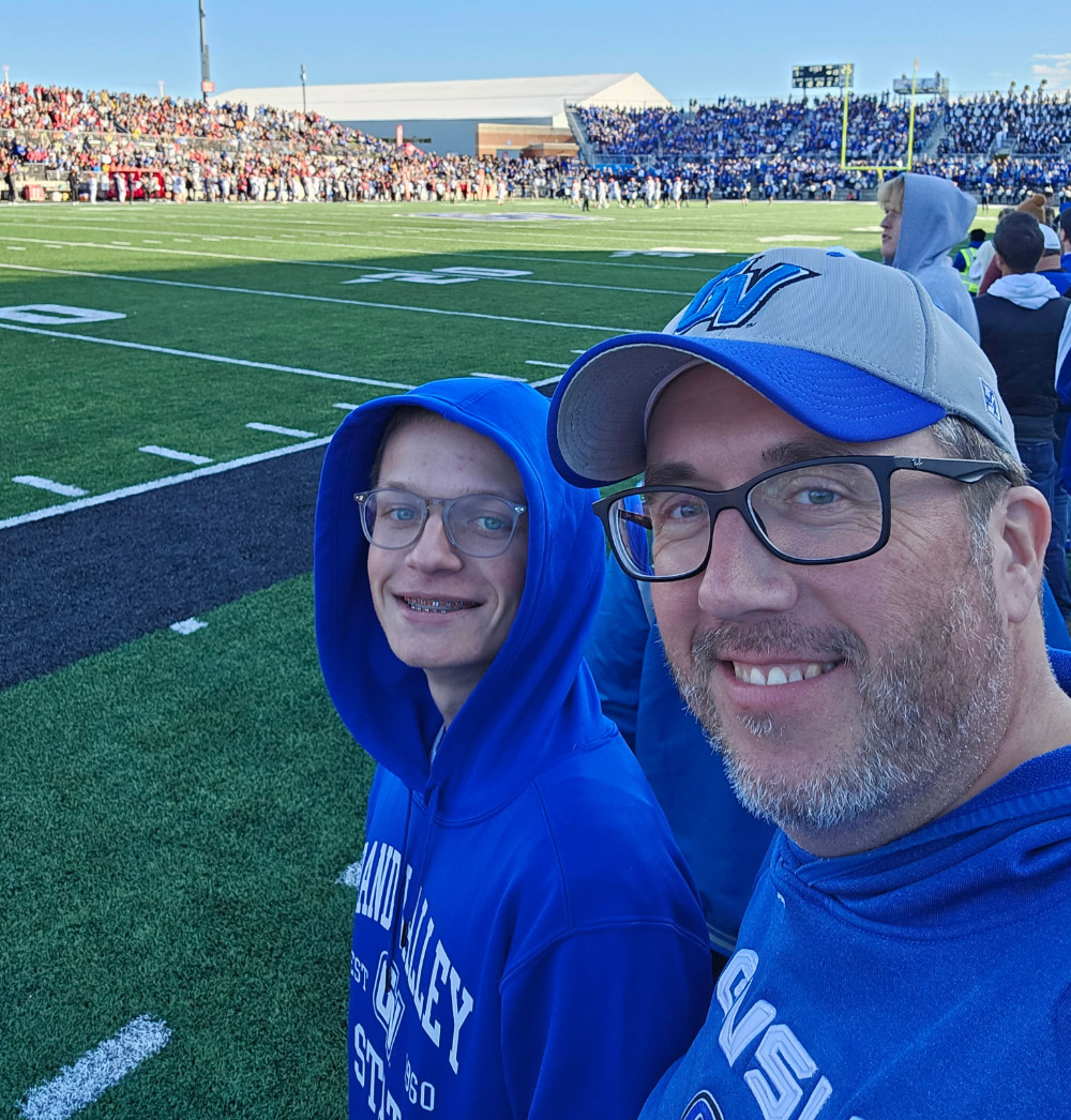 at GVSU football game are Mike Eichberger and his stepson Tristan, both are wearing Laker blue