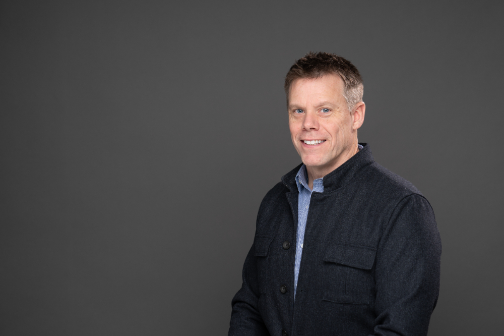 Christian Glupker in a dark jacket and open collar blue shirt