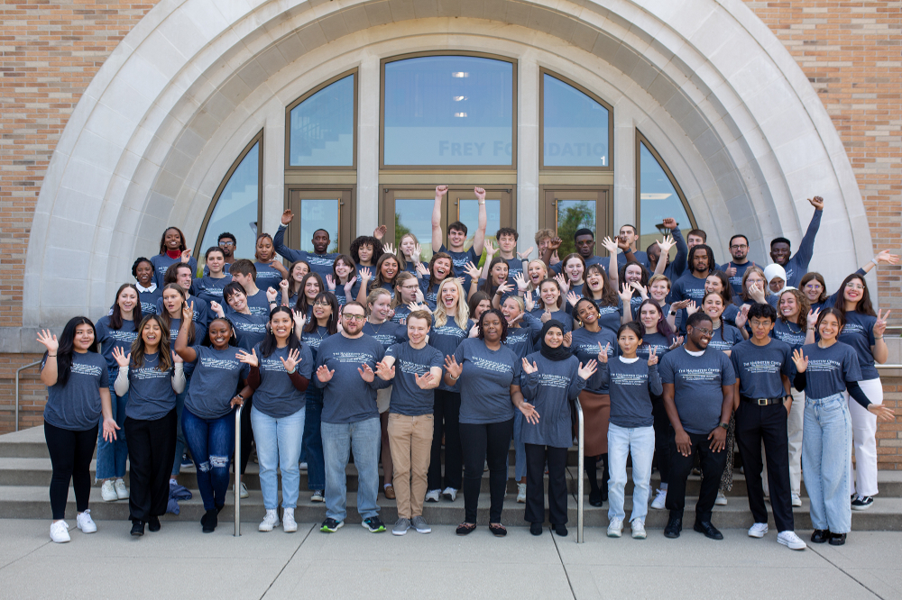 large group of Cook Leadership Fellows cheering in front of the L. William Seidman Center