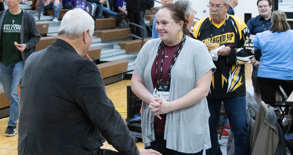 two people talking on gymnasium floor, others in background