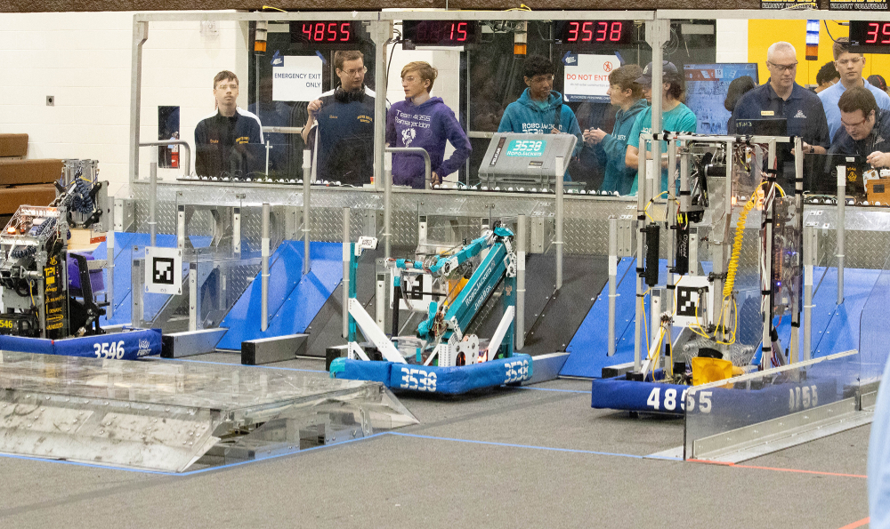 robots ready for competition, teams standing behind