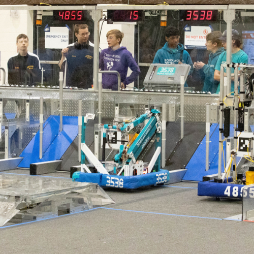 robots ready for competition, teams standing behind
