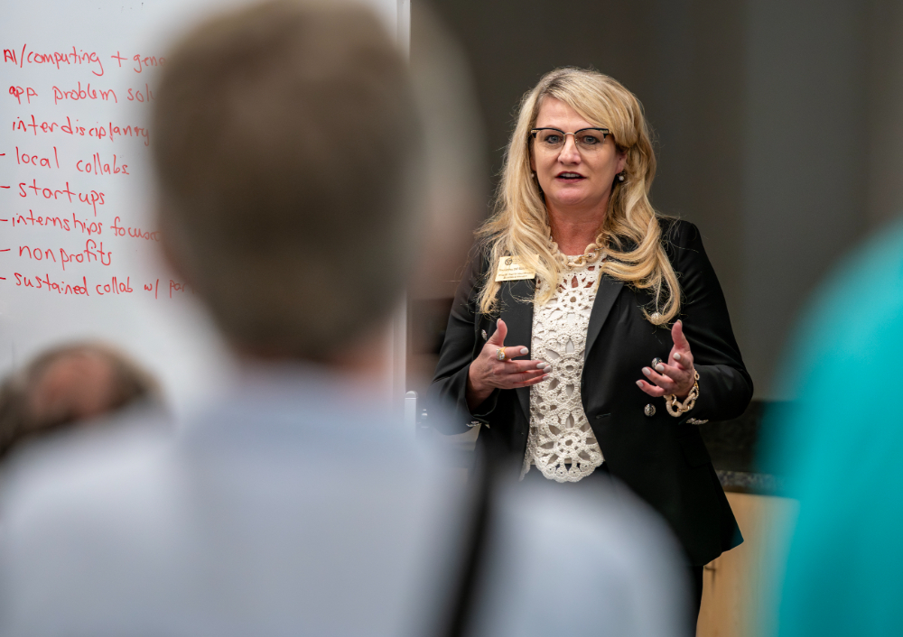 Sherri Fannon in front of room next to whiteboard with red ink writing