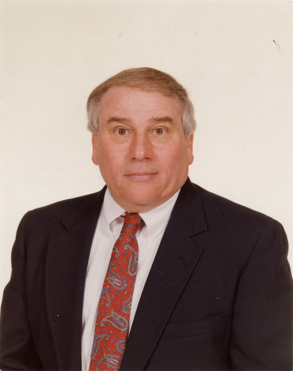 Don Thomas seated for portrait with dark suit jacket and white shirt