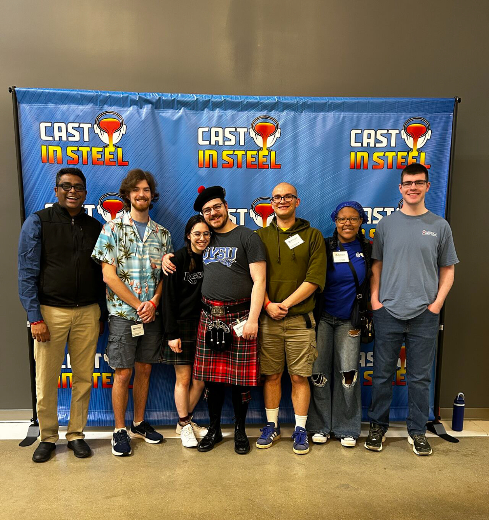 seven people lined up in front of a Cast in Steel backdrop