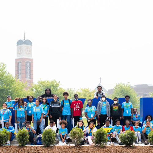 group of middle school students in front of the Laker Letters, carillon tower in the background