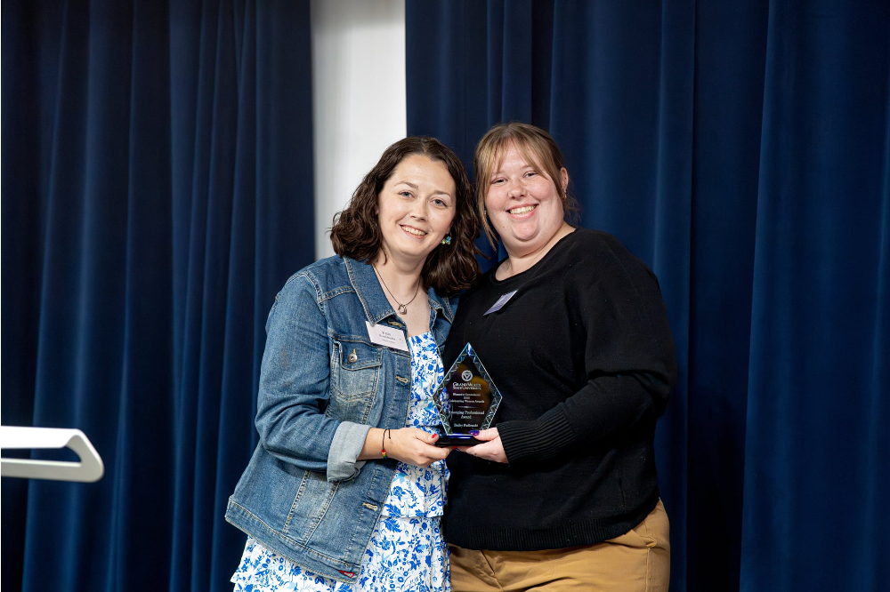 Katie Perschbacher and Bailey Pudlowski next to each other with a glass award