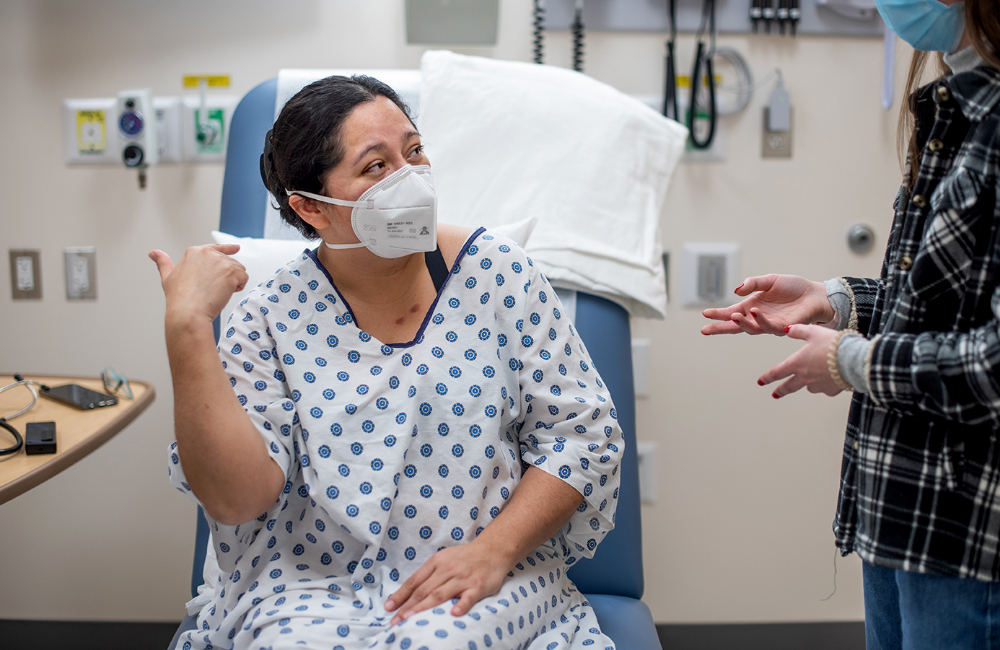 Miriam Johnston, a standardized patient trained to speak only in Spanish, communicates with Alyssa Bartle, at right, during a simulation in the Cook-DeVos Center for Health Sciences. Johnston has makeup on her chest created to look like cigarette burns.