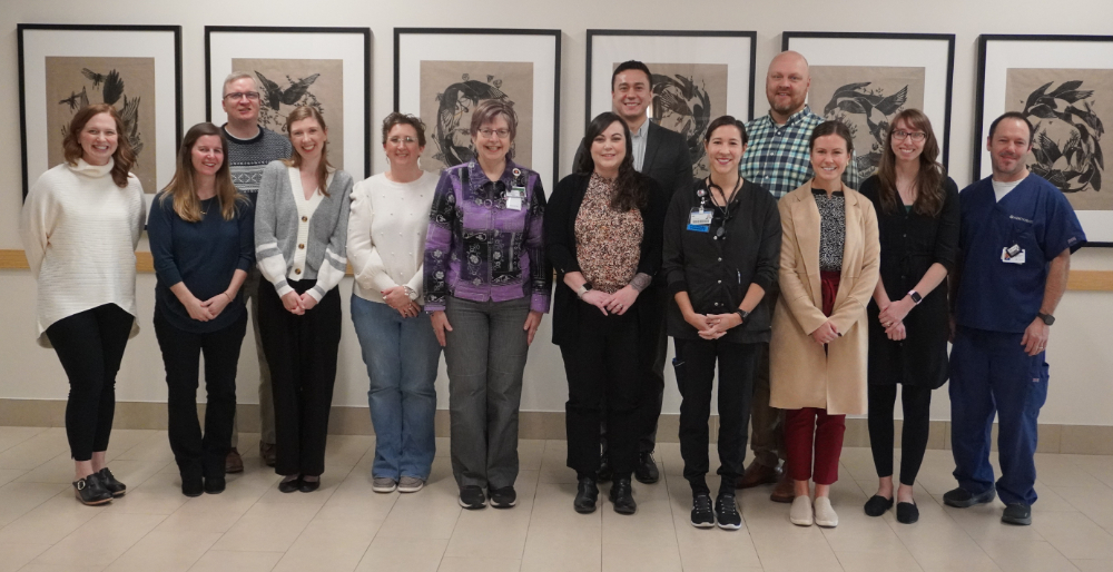 group of people standing in a hallway in front of six framed pieces of artwork