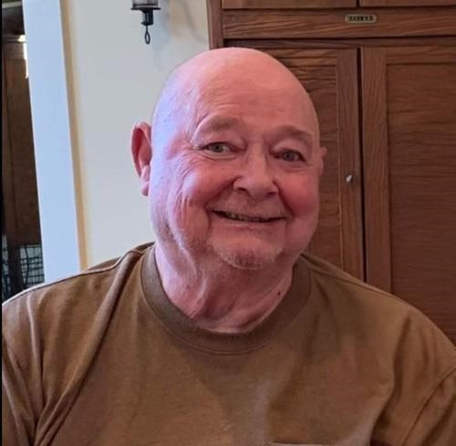Bob Bauer in a brown tshirt seated in front of tall cabinet