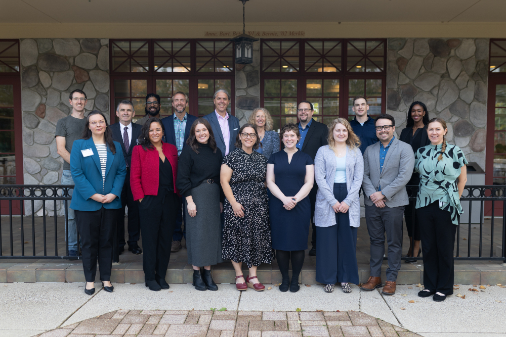 two rows of people standing outside of the alumni house