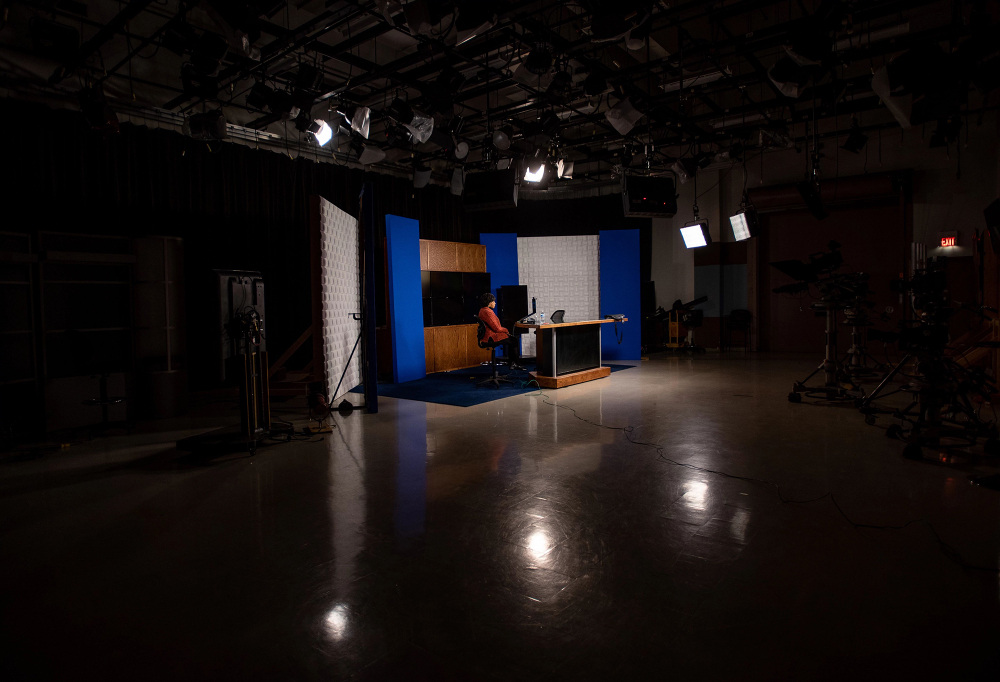 woman in darkened tv studio with spotlights lighting her