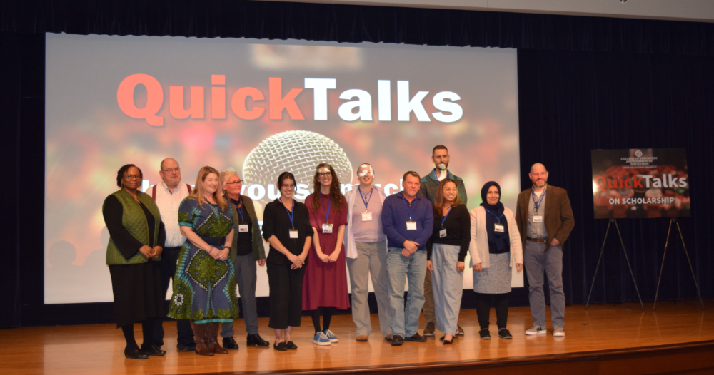 large group of people standing on stage in Loosemore Auditorium in front of screen, QuickTalks