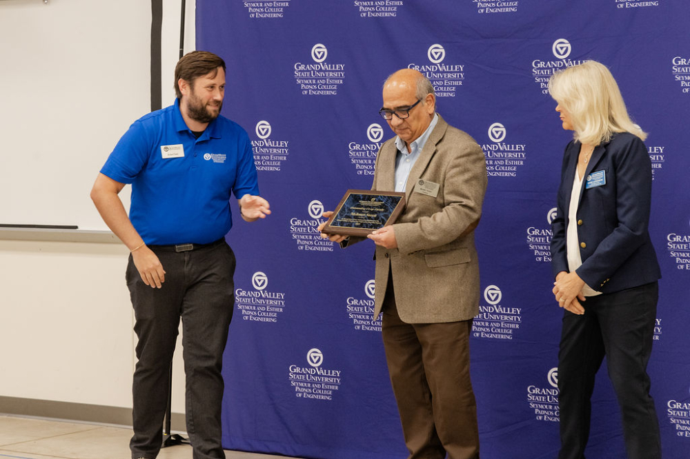 Mehmet Sozen, center, accepts an award as Co-Op Faculty Advisor of the Year from Ethan Tanis, left, and Diane LaFreniere.